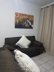 eine schwarze Couch in einem Wohnzimmer mit einem Gemälde in der Unterkunft PITANGUEIRAS BEACH in Guarujá