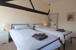 two beds in a bedroom with white sheets and towels at The Mill at Rose Villa Farm in Hereford