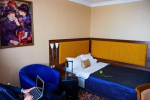 ein Hotelzimmer mit einem Bett und einer Person mit einem Laptop in der Unterkunft Congress Hotel Malakhit in Tscheljabinsk