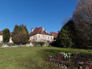uma casa grande num campo verde com árvores e flores em Le Clos - La chapelle em Lombard