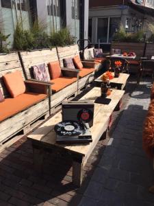 a group of benches with orange cushions and a television at Slapen bij Café de Concurrent in Vlissingen