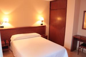 
a hotel room with a bed, dresser and a lamp at Hotel Maycar in A Coruña
