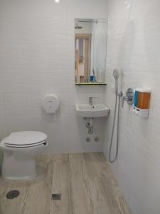 a white bathroom with a toilet and a sink at Albergue La Magia del Camino in Comillas