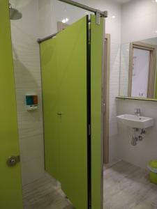 a green shower door in a bathroom with a sink at Albergue La Magia del Camino in Comillas