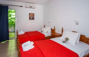 two beds in a room with red and white sheets at Musses in Kókkinon Nerón