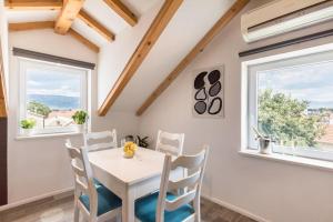 una sala da pranzo con tavolo bianco, sedie e finestre di Guest House Kala a Spalato (Split)