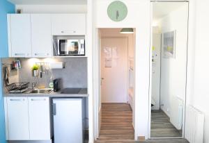 une cuisine avec des placards blancs et un couloir dans l'établissement Studio en centre ville avec garage et wifi, à La Grande Motte