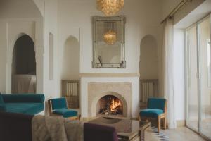 a living room with a fireplace and blue chairs at Les Deux Tours in Marrakech