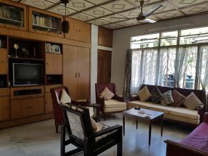 a living room with a couch and chairs and a tv at Vamoose Madhumita Homestay in Guwahati