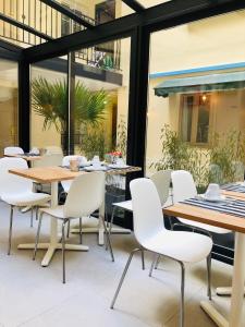Un comedor con mesas y sillas blancas. en Marmotel Etoile, en París