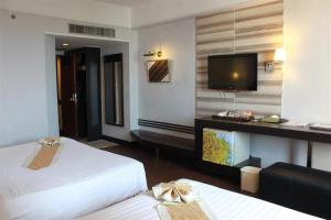 a hotel room with two beds and a flat screen tv at Charoen Thani Hotel, Khon Kaen in Khon Kaen