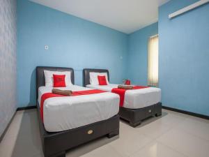 two beds in a room with blue walls and red pillows at RedDoorz @ Raya Tidar in Malang