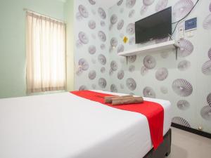 - une chambre avec un lit et une télévision murale dans l'établissement RedDoorz @ Raya Tidar, à Malang