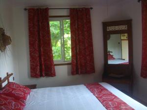 1 dormitorio con 1 cama con cortinas rojas y espejo en Les Cottages de Bellevue Ecolodge, en Port Vila