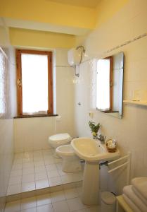 a white bathroom with a toilet and a sink at Casa Milena in San Gimignano