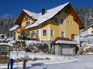 a yellow house with a snow covered roof at Haus ÖtscherTeufel in Lackenhof