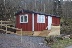 eine rote Hütte mit einer weißen Tür und einer Veranda in der Unterkunft Stuga på Hammarbergs Gård in Kungsbacka