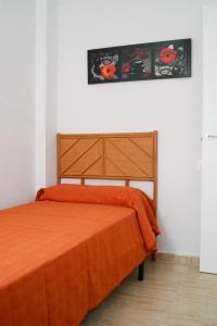 1 dormitorio con 1 cama con manta naranja en Apartamentos Riviera Beach, en Pilar de la Horadada