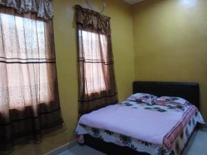 a bedroom with a bed and two windows at Malinja Home in Pantai Cenang