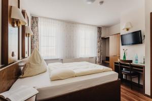 a bedroom with a bed and a desk and a television at Hotel Restaurant 7 Berge am Schlehberg in Alfeld
