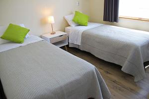 two beds in a hotel room with green pillows at Departamentos Nómades del Lago in Puerto Varas