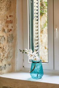 een blauwe vaas met bloemen op een vensterbank bij La Rocca Apartment Old Town Kotor in Kotor