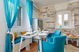 a dining room with a glass table and blue chairs at La Rocca Apartment Old Town Kotor in Kotor