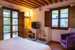 1 dormitorio con 1 cama y escritorio con TV en Castell de la Solana, en Alcalalí
