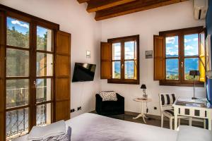 a bedroom with a bed and a desk and windows at Castell de la Solana in Alcalalí