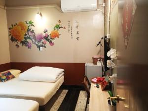 um quarto com duas camas com flores na parede em Tainan-Inn em Tainan