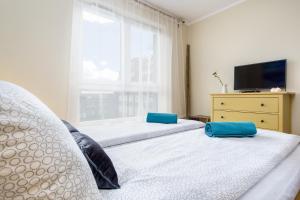 a bedroom with two beds and a tv and a window at Elite Apartments Cityview Center in Gdańsk