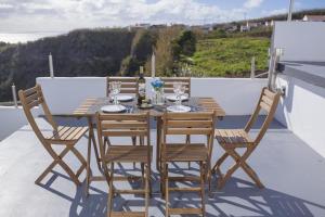 a wooden table with four chairs and a bottle of wine at Água de Alto Terrace House in Água de Alto