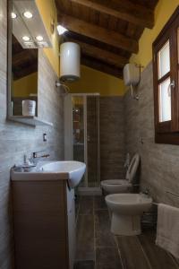 een badkamer met een wastafel, een toilet en een spiegel bij Arroccas de is Istellas in Arbus