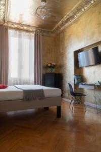 - une chambre avec un lit, une chaise et une télévision dans l'établissement Rivière Private Rooms at the Park, à Milan