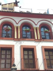 - un bâtiment avec des fenêtres et des balcons fleuris dans l'établissement El Capricho de San Fernando, Consigna gratis y Parking a 200mts, à Cordoue