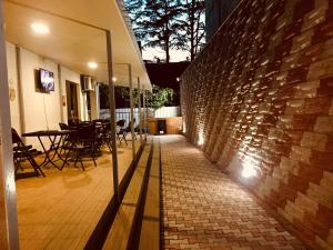 a brick wall and a patio with tables and chairs at Cottage Euro Style in Ureki