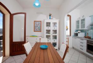 cocina con mesa de madera y armarios blancos en Quadrilocale Laura, en Santa Teresa Gallura