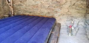 - un lit bleu dans une grotte avec un mur en pierre dans l'établissement U paliaghju, une cabane de berger pour vivre un dépaysement total, à Santa-Lucia-di-Mercurio