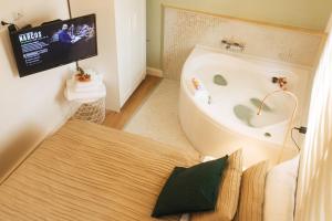 łazienka z wanną, telewizorem i łóżkiem w obiekcie Stampace Apartments w Cagliari