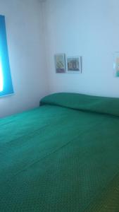 - une chambre avec un lit vert et des draps verts dans l'établissement La municeddha, à Cannole