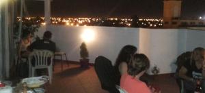 un grupo de personas sentadas en un balcón por la noche en Hostal del Milagro en Salta