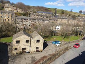 an old stone building with cars parked in a parking lot at Crosland Cottage in Holmfirth