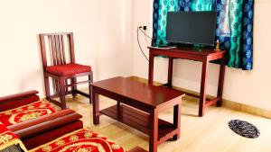 a living room with a tv and a table and a chair at Blue Bridge Homes in Port Blair