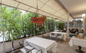 un patio avec des tables blanches, des chaises et des arbres dans l'établissement Ca' Nova, à Marghera