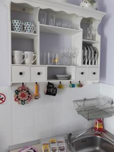 una cocina con armarios blancos con vajilla y fregadero en Apartments & Rooms No.1, en Zadar