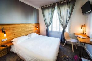 a bedroom with a white bed and a desk and a window at Hôtel Victor Hugo Lorient in Lorient