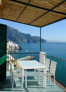un tavolo bianco e sedie su un balcone con vista sull'oceano di Amalfi Blue FLowers B ad Amalfi