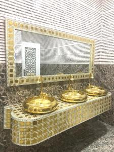 Tres lavabos de oro en un baño con espejo en Al Rayyan Hotel Apartments Muscat, en Seeb