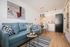 a living room with a blue couch and a kitchen at Studio 49 Apartment in Ełk