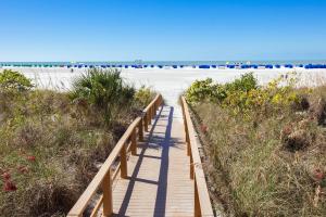 a wooden walkway leading to a beach with palm trees at GullWing Beach Resort in Fort Myers Beach